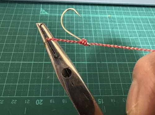 プライヤーで糸を締めこむ